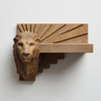3D printed lion head wall shelf with Art Deco sunburst backplate and stepped geometric floating ledge, mounted on a clean minimalist wall.