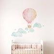 A soft watercolor illustration of a pink and pale orange hot air balloon floating above several whimsical, swirling teal and light green clouds on a plain white background.