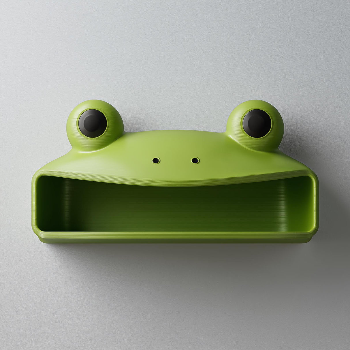 3D printed cute frog wall shelf with big round eyes and open storage compartment, mounted on a light modern interior wall.