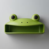 3D printed cute frog wall shelf with big round eyes and open storage compartment, mounted on a light modern interior wall.