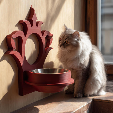 3D printed gothic wall mounted pet bowl holder with ornate frame and circular cutout for a bowl, photographed by a sunny window with a cat nearby.