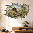 3D broken wall vinyl decal showing a watercolor Japanese garden with a pagoda, arched bridge, trees, and pond reflection inside a cracked wall opening.