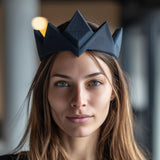 Adult woman wearing a black geometric 3D printed crown headpiece with sharp angular design in a modern gothic interior setting.