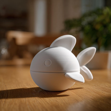 3D printed fish memorial urn with removable lid displayed on a wooden table in warm indoor lighting.