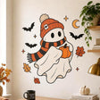 Cute white cartoon ghost wearing an orange knit beanie and black-and-orange striped scarf while holding a small pumpkin, surrounded by black bats, a golden crescent moon, stars, and orange autumn leaves on a white background.