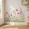 Watercolor meadow of delicate wildflowers in pink, coral, yellow, lavender, violet, and soft blue, growing among tall grasses, slender stems, and layered green foliage.