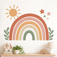 Terracotta, peach and mustard rainbow wall decal with a small sun, four stars and sage-green leafy sprigs.