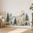 Watercolor-style mountain wall decal with blue-gray peaks, an ochre sun, teal evergreens, sage trees, birds and grasses.
