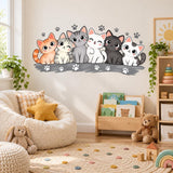 Six cute cats nursery wall art with orange, cream and gray cats seated together above scattered paw prints.