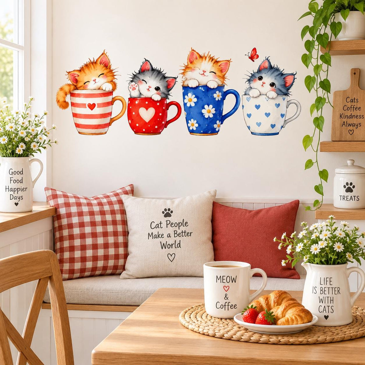 Four kittens in decorated teacups wall sticker above a cozy kitchen breakfast nook with cat-themed pillows and flowers.