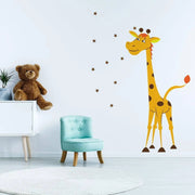 Cute giraffe wall decal in a nursery with a teddy bear and blue chair.