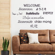 Decorative wall with multilingual 'Welcome' wall sticker above a modern couch.